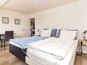Et pænt og ryddeligt værelse med seng, natbord, lampe og en stol.