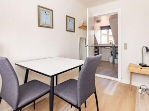 A dining area with a table and chairs, a kitchen in the background, and a door leading to another room. - 3 Person Holiday Home in Aeroskobing (Aeroskobing)