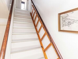 A wooden ladder leaning against a white staircase with a framed map on the wall. - 3 Person Holiday Home in Aeroskobing (Aeroskobing)
