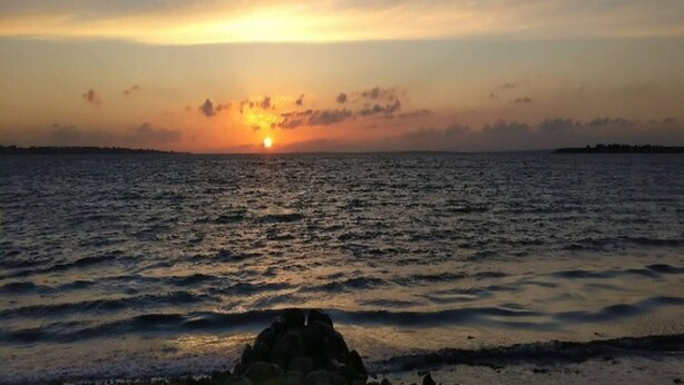 A sunset over a calm sea with a rocky shoreline. - 3 Person Holiday Home in Aeroskobing (Aeroskobing)