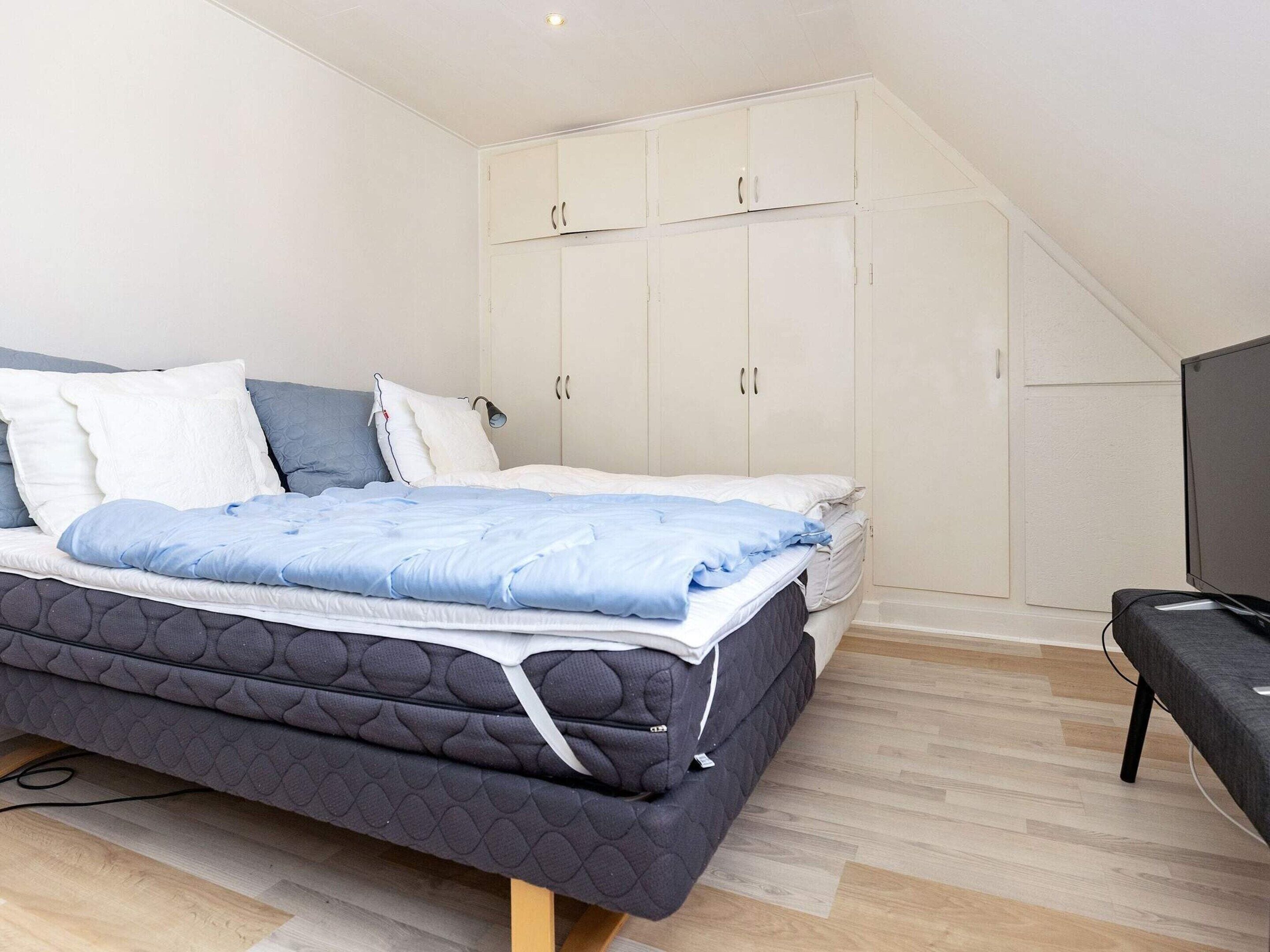 A bedroom with a bed, wardrobe, and a television.