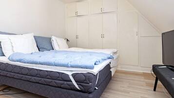 A bedroom with a bed, wardrobe, and a television.