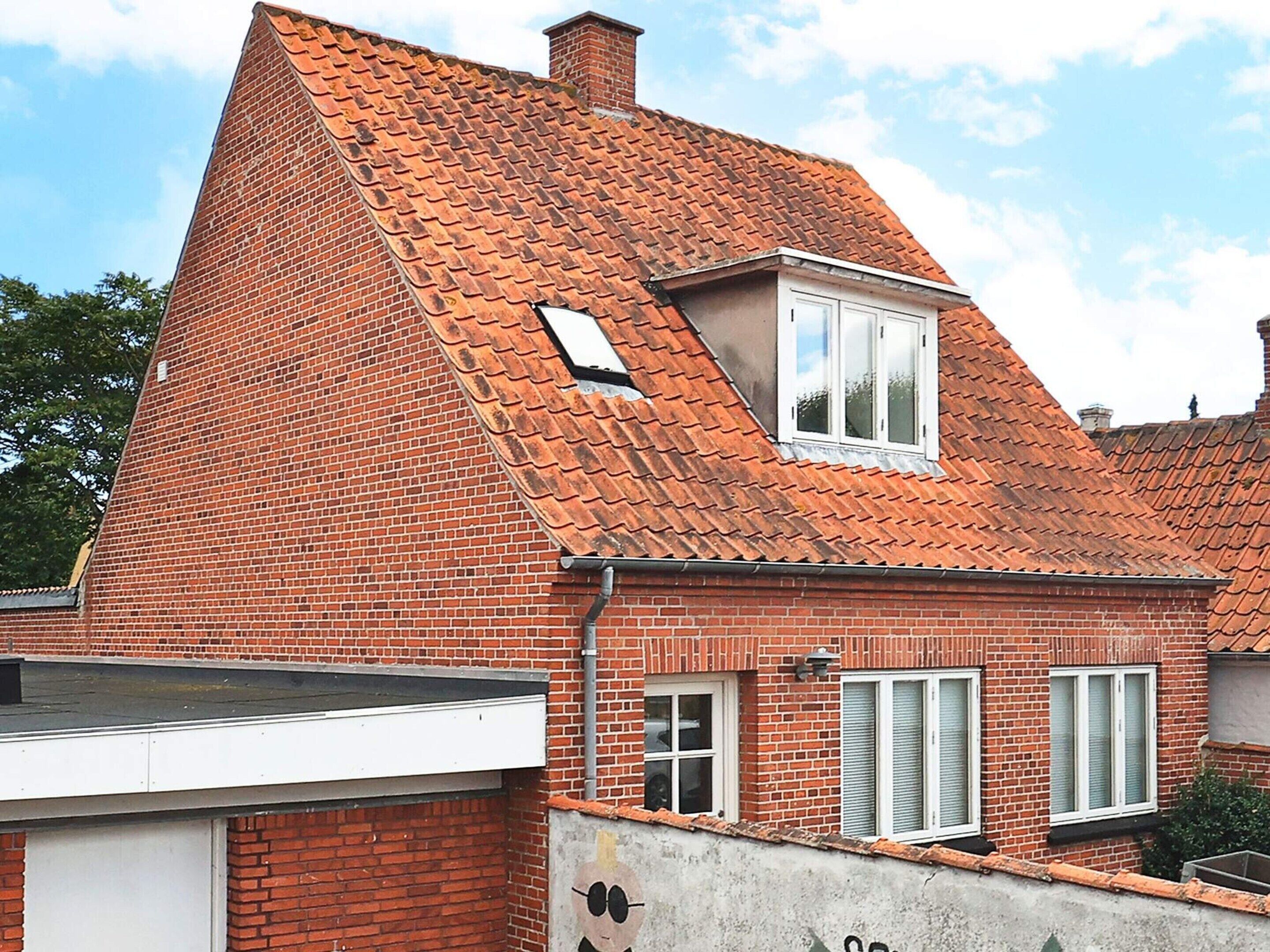 Een huis met rode bakstenen, een schuin dak, een klein dakvenster en een garage.