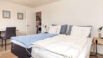 A neatly arranged bedroom with a bed, bedside table, lamp, and a chair.