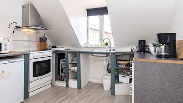 A compact kitchen with a stove, oven, and a coffee maker.