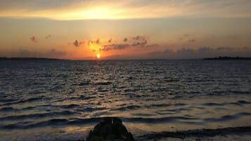 A sunset over a calm sea with a rocky shoreline.