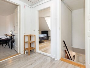 A room with a bed, a desk, and a chair, with a wooden floor and white walls. - 3 Person Holiday Home in Aeroskobing (Aeroskobing)