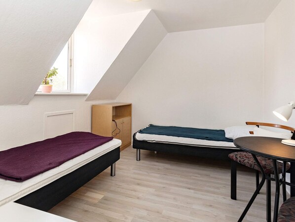 A dormitory room with two beds, a desk, a chair, and a window. - 3 Person Holiday Home in Aeroskobing (Aeroskobing)