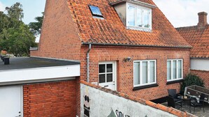 A two-story brick house with a sloped roof, a small attic window, and a visible chimney. - 3 Person Holiday Home in Aeroskobing (Aeroskobing)