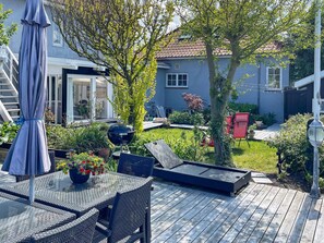 A patio with outdoor furniture, a barbecue grill, and a garden area with various plants and a tree. - 6 Person Holiday Home in Otterup (Otterup)