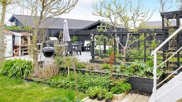 A garden with raised beds, a barbecue area, and outdoor furniture.