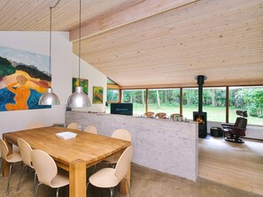 Un espace de repas moderne avec une table et des chaises en bois, une cheminée et une vue sur l’extérieur.