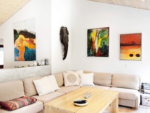 En stue med en beige sofa, et træbord og tre billeder på væggen.