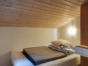 Een eenpersoonsbed met een gewatteerd matras, kussens en een nachtkastje met een lamp.