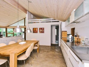 A modern kitchen with a wooden dining table, chairs, and pendant lights. - 4 Star Holiday Home in Farevejle (Faarevejle)