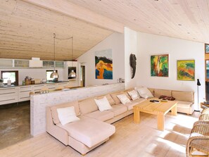 A modern living space with a kitchen, a large beige sofa, and artwork on the walls.