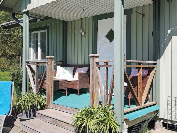A covered porch with a seating area, a pool, and potted plants.