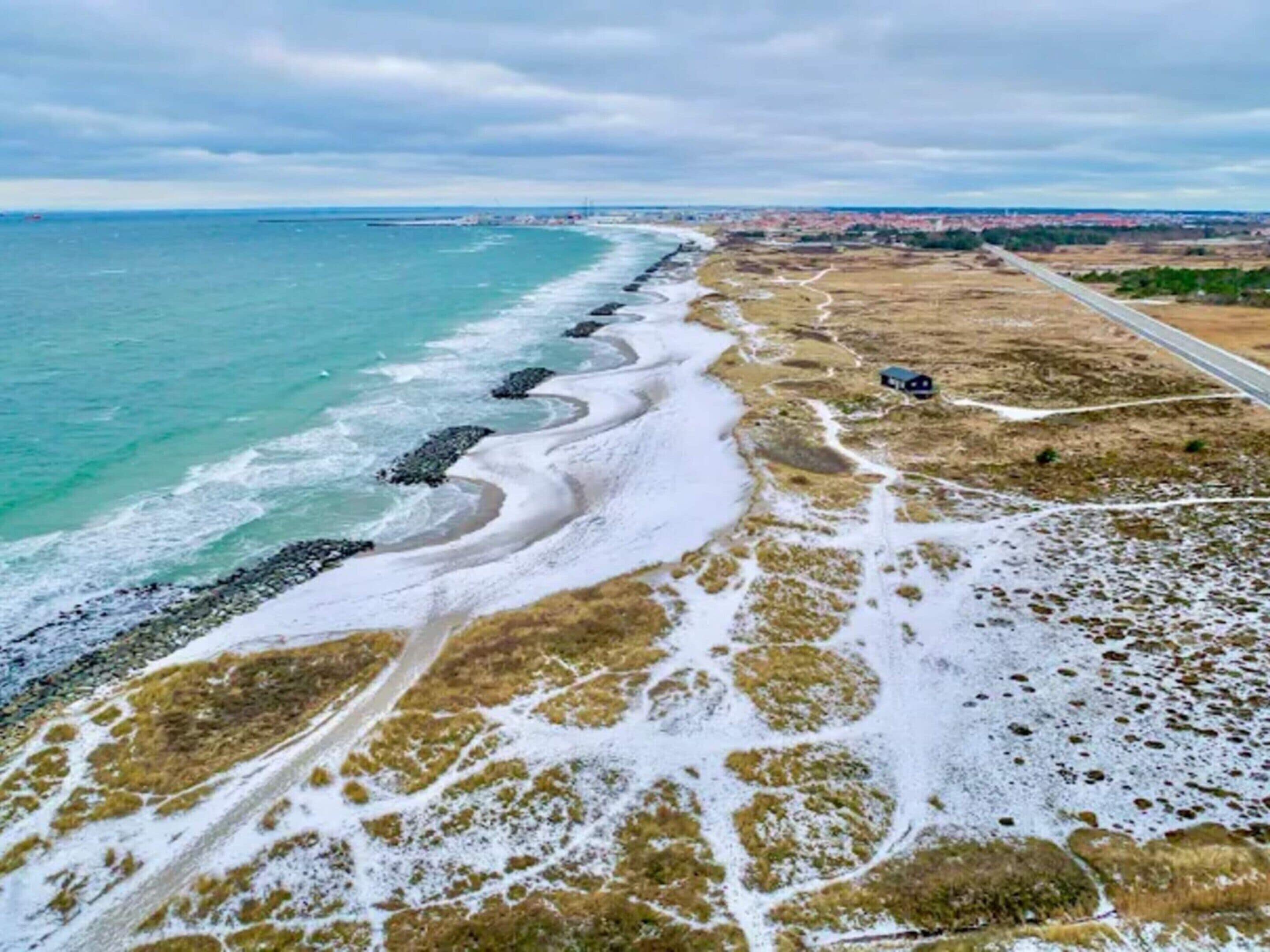 Una carretera costera con una playa a un lado y una vía al otro.