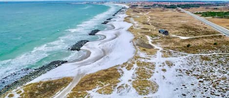 Una carretera costera con una playa a un lado y una vía al otro.