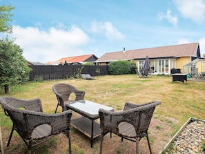 A backyard with a dining set, a covered patio, and a house in the background.