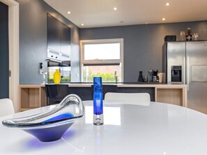 Una cocina moderna con una mesa blanca, un objeto de vidrio azul y una ventana.