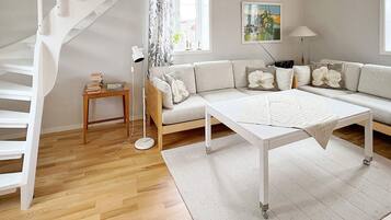 A modern living room with a white sofa, a coffee table, a floor lamp, and a staircase.