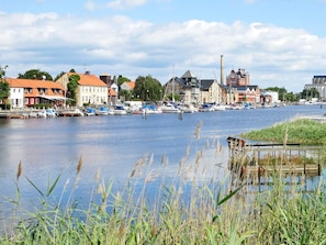 En stad vid en flod med byggnader, båtar och en brygga.
