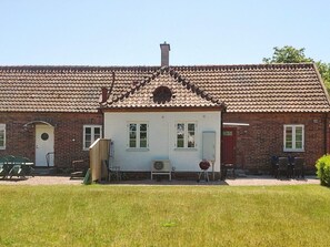 En tvåvåningsbyggnad i tegel med ett tak täckt av takpannor, en liten veranda och en gräsplätt.