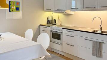 Una cocina moderna con armarios blancos, estufa y lavamanos.