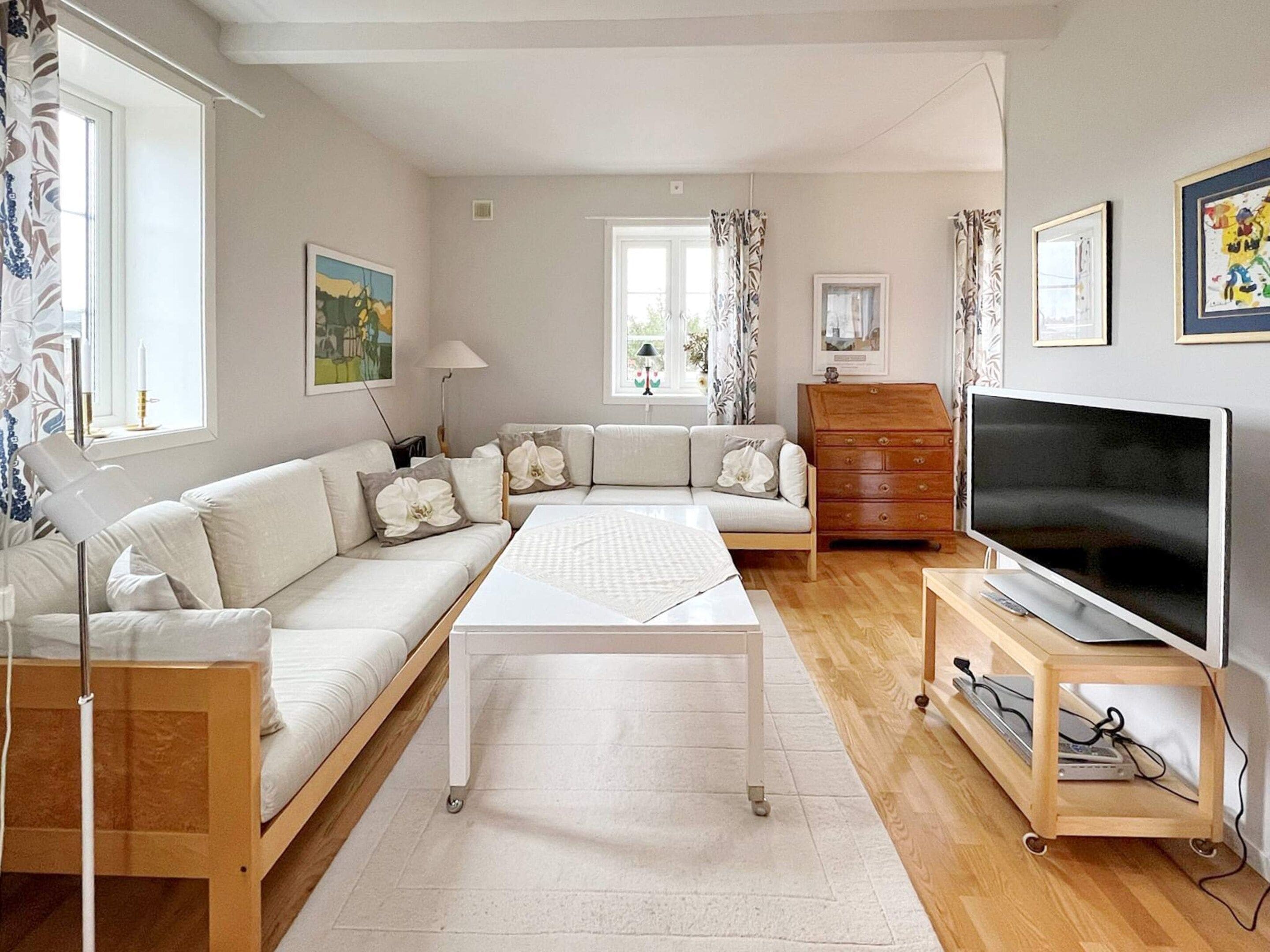 A modern living room with a sofa set, a coffee table, a TV on a stand, and a wooden dresser.