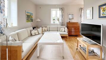 A modern living room with a sofa set, a coffee table, a TV on a stand, and a wooden dresser.