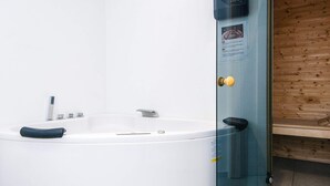 A modern bathroom with a freestanding bathtub, a glass shower enclosure, and a wooden wall. - 10 Person Holiday Home in Sjolund (Sjølund)