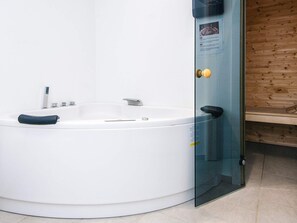 Ein modernes Badezimmer mit einer freistehenden Badewanne, einer Duschkabine aus Glas und einer Holzvertäfelung.