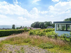 Ein modernes Haus mit einem großen Panoramafenster, umgeben von einem gepflegten Garten und Blick aufs Meer.