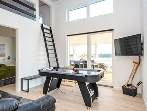 Ein modernes Wohnzimmer mit Kicker, einer Couch, einem Fernseher und einem Balkon mit Blick.