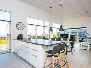 A modern kitchen with a large island, white cabinetry, and a clock on the wall.