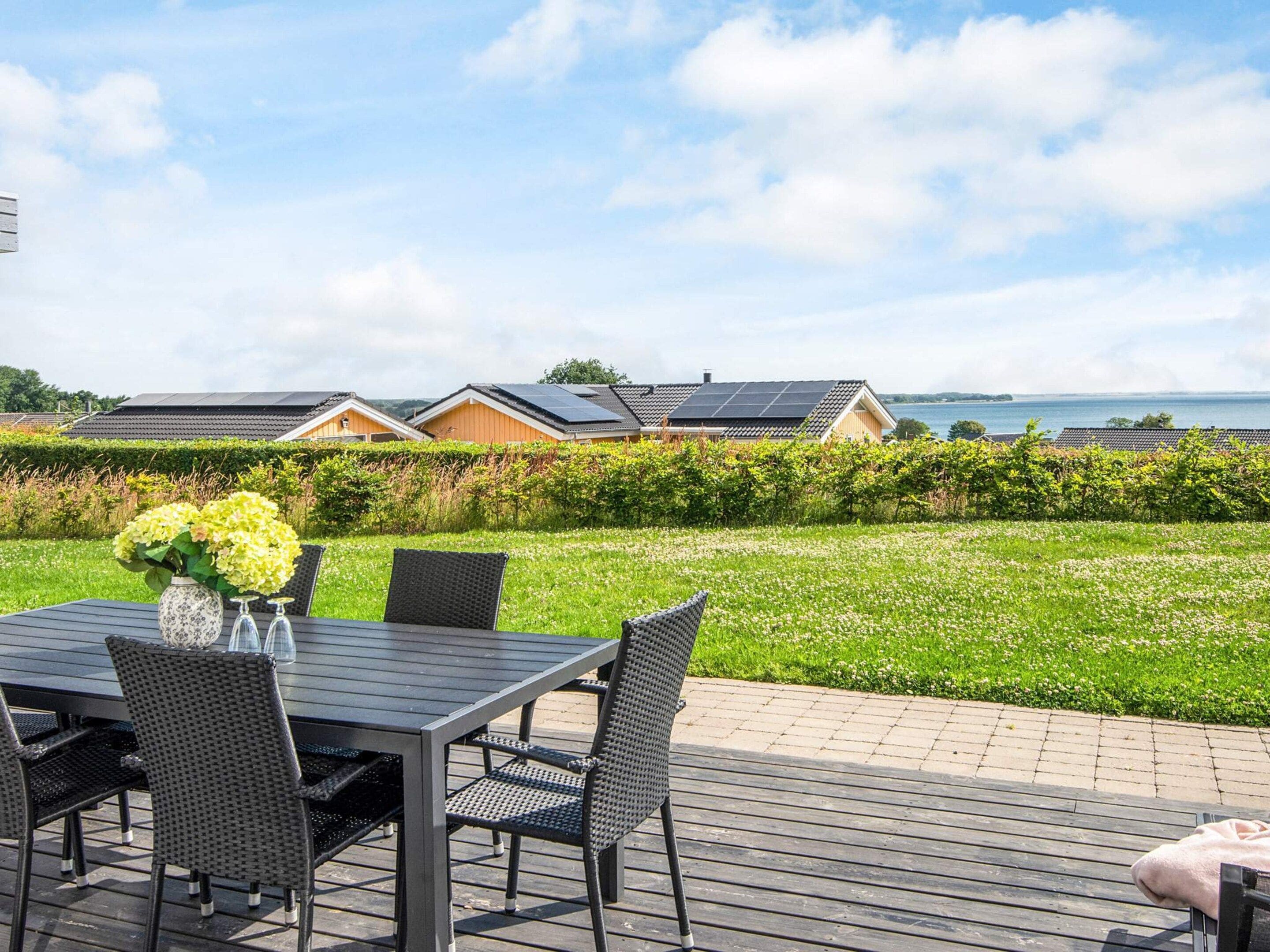 Eine Terrasse mit Tisch und Stühlen, einer Blumenvase und Blick auf Häuser mit Solaranlagen.
