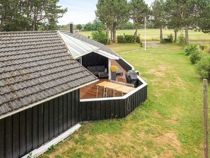A wooden deck attached to a house with a sloped roof, a barbecue grill, and a seating area with a table and chairs. - 7 Person Holiday Home in Graested (Gilleleje)