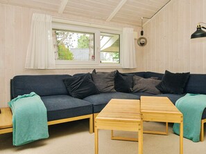 A cozy room with a dark blue sofa, a wooden table, and a window with curtains. - 7 Person Holiday Home in Graested (Gilleleje)