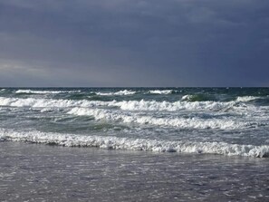 Uma praia com ondas e céu nublado.