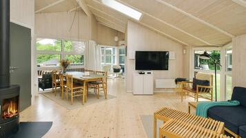 Amplia sala de estar con chimenea, muebles de madera, un televisor y ventanas grandes.