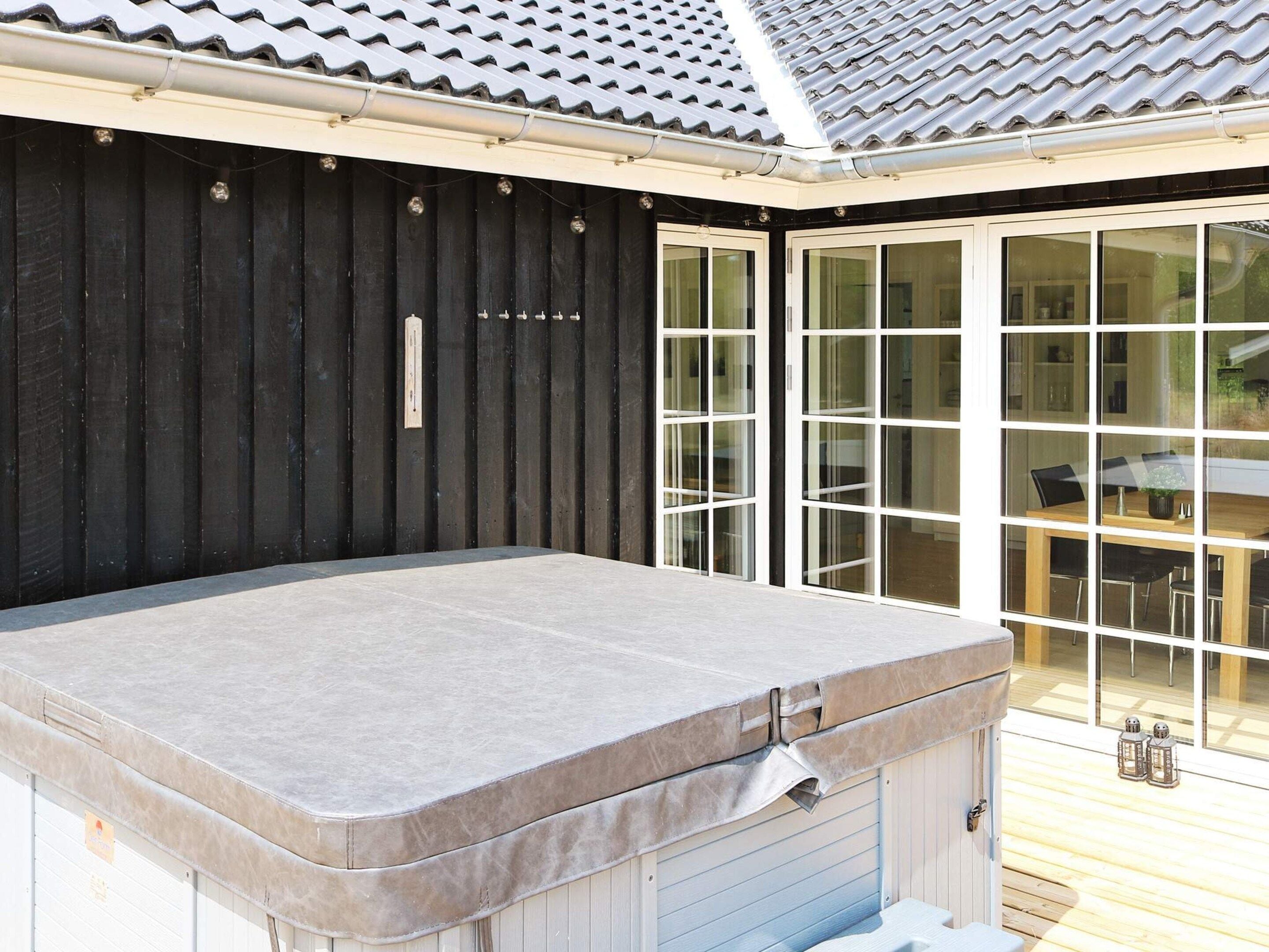 Een bubbelbad met een houten terras en een schuifdeur naar een eethoek.