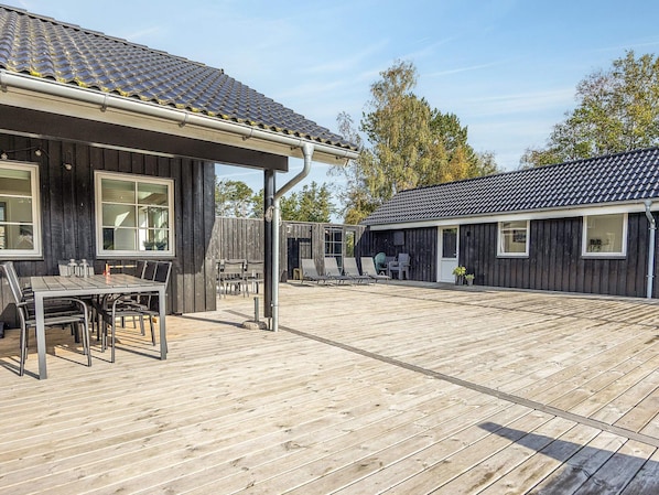 A wooden deck with a dining area, outdoor seating, and a covered section.