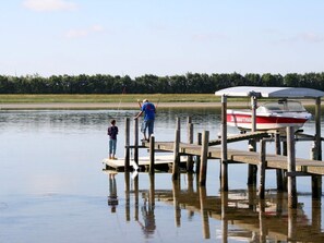 A wooden dock extending into a calm body of water with a boat docked at the end.