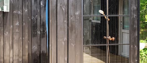 A wooden structure with a glass door leading to a wooden deck.