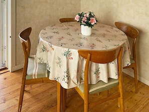 A round dining table with a floral tablecloth, surrounded by wooden chairs. - 4 Person Holiday Home in Vetlanda (Vetlanda)
