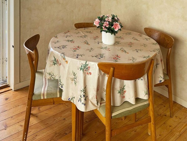 Ein runder Esstisch mit einer blumigen Tischdecke, umgeben von Holzkästen.