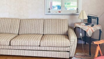 A living room with a sofa, a small table with a lamp, and a chair.