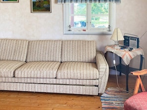 Una sala de estar con un sofá, una mesita de noche con una lámpara y una silla.