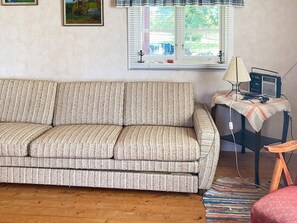 Ein Wohnzimmer mit einer Couch, einem kleinen Tisch mit einer Lampe und einem Sessel.